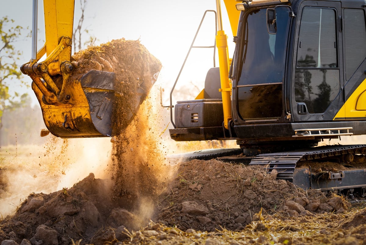 Excavator digging and shaping soil on site